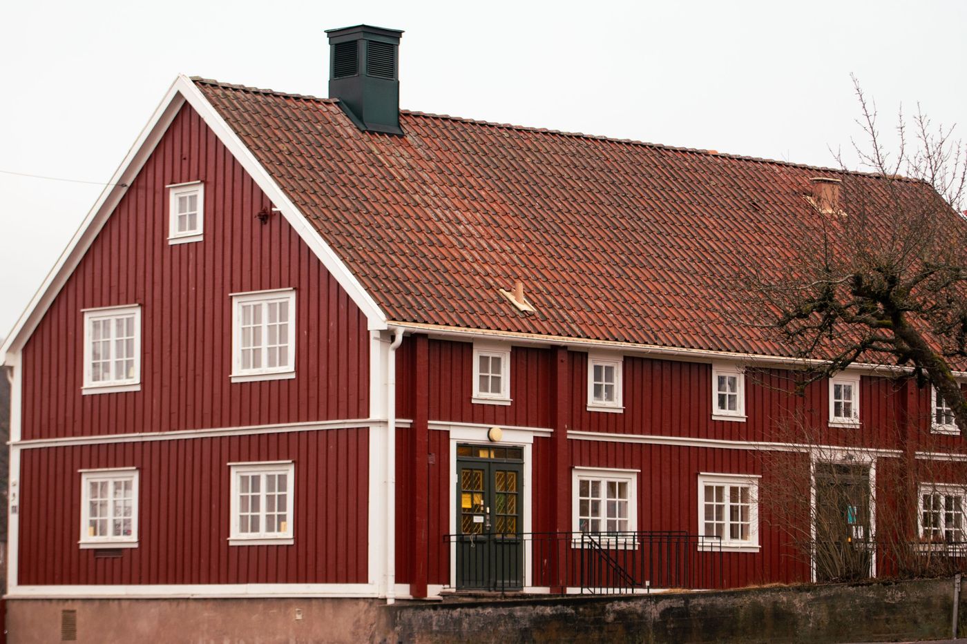 Rödmålad träbyggnad med nyrenoverat tegeltak och vita fönsterfoder